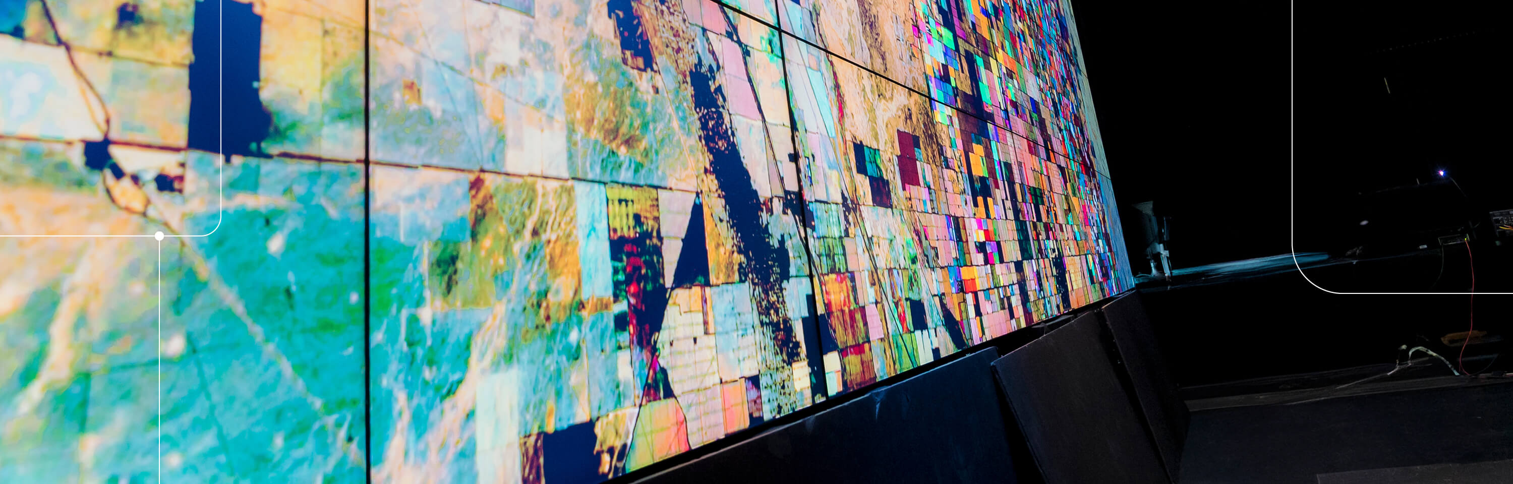 A visualization wall of monitors, showing various colorful shapes, representing data from GIS mapping